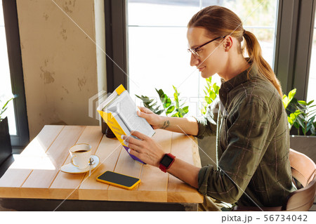 Handsome positive man being focused on reading Handsome positive man being focused on reading 56734042