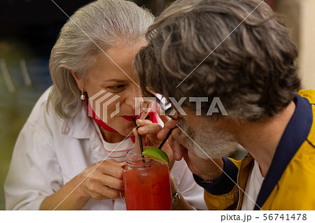 Loving couple drinking their cold smoothie together. Loving couple drinking their cold smoothie together. 56741478