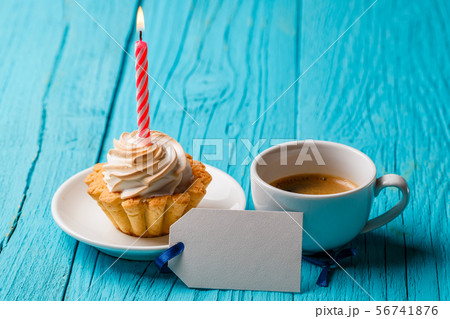 Shortcake with cream and a candle, with a cup of coffee and a blank card on a blue table Shortcake with cream and a candle, with a cup of coffee and a blank card on a blue table 56741876