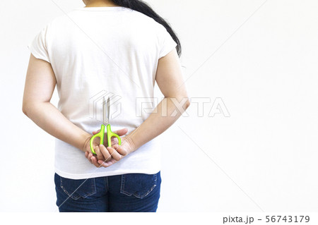 背中にハサミを隠した女性の後ろ姿 56743179