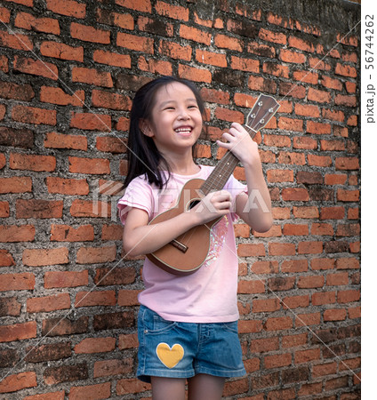 Little asian child play the ukulele, old brick Little asian child play the ukulele, old brick 56744262