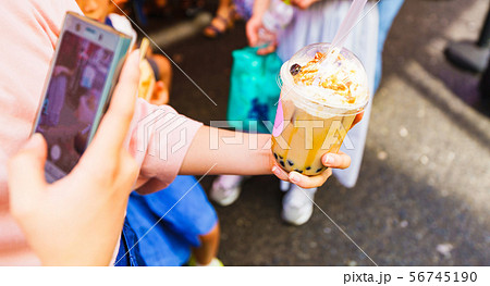 [原宿文化イメージ] 流行に敏感な少女がタピオカミルクティーを買ってスマホでSNSに投稿するシーン 56745190