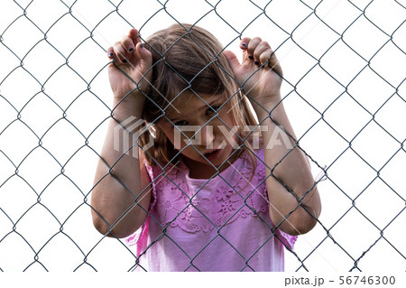 Sad girl behind metal wire mesh fence 56746300