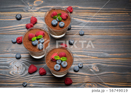Classic tiramisu dessert with blueberries and strawberries in a glass cup on wooden background 56749019
