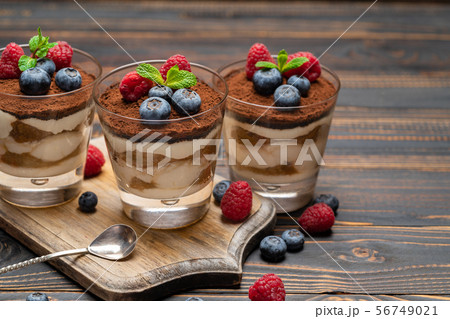 Classic tiramisu dessert with blueberries and strawberries in a glass cup on cutting board on wooden 56749021