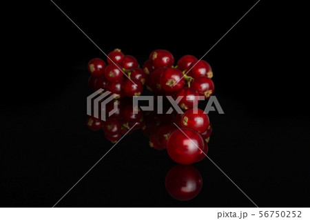 Fresh red currant isolated on black glass Fresh red currant isolated on black glass 56750252