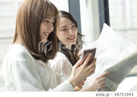 窓辺 スマホ 新聞 女性 二人 56751943