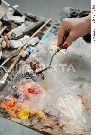 Woman artist draws a palette knife. Oil paints of different colors on the palette. 56757965