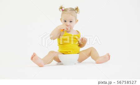 Funny baby girl eats her meal with a spoon Funny baby girl eats her meal with a spoon 56758527
