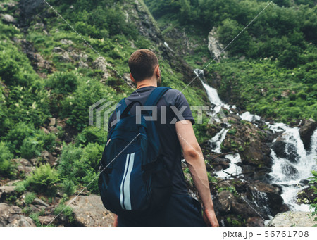 Young man looking at mountain stream in the forest admires nature. 56761708