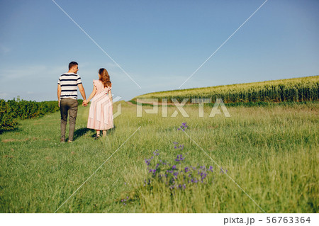 Beautiful couple spend time on a summer field Beautiful couple spend time on a summer field 56763364