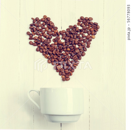 Grain of coffee in the form of a heart over a cup. Grain of coffee in the form of a heart over a cup. 56778093
