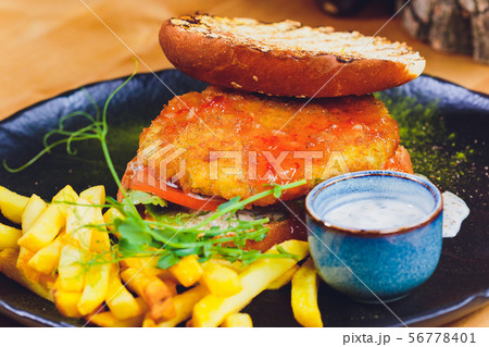 Vegetarian lentil burger in wholewheat bun with lettuce, tomato and cucumber accompanied by French Vegetarian lentil burger in wholewheat bun with lettuce, tomato and cucumber accompanied by French 56778401
