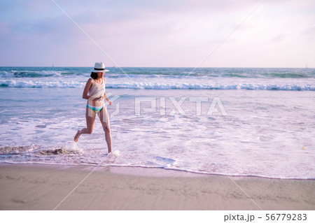 young woman on sunset beach and joyful running . young woman on sunset beach and joyful running . 56779283
