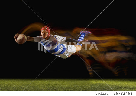 One caucasian man playing rugby on the stadium in mixed light One caucasian man playing rugby on the stadium in mixed light 56782462