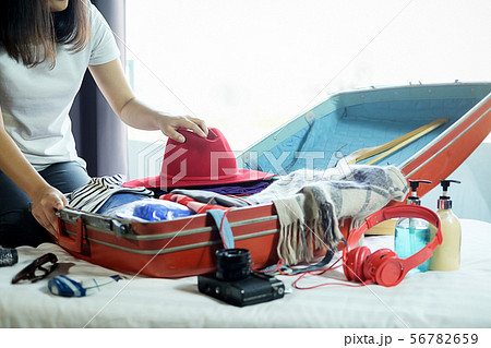People packed suitcase with travel accessories on 56782659