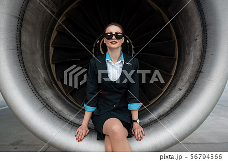 Charming Caucasian woman posing for camera near airplane engine 56794366