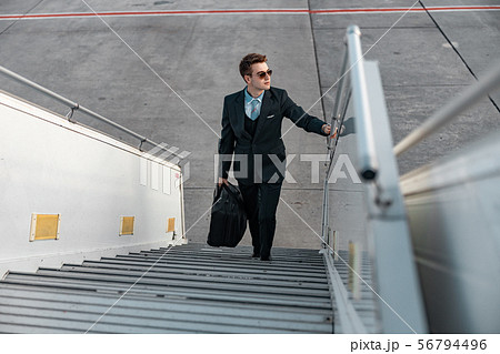 Businessman going up on plane ladder in airport Businessman going up on plane ladder in airport 56794496