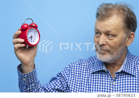 Elderly man in eyeglasses with a little red clock Elderly man in eyeglasses with a little red clock 56795623