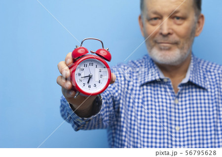 Elderly man in eyeglasses with a little red clock 56795628