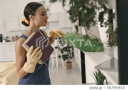 Serene lady dusting bookcase at home stock photo Serene lady dusting bookcase at home stock photo 56795933