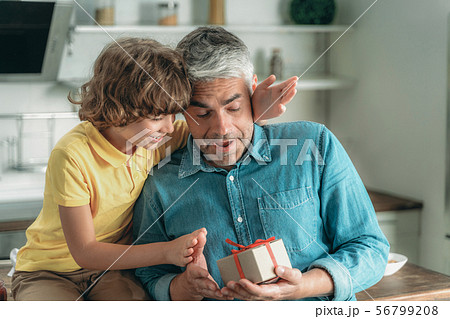 Son making surprise and gives father present box Son making surprise and gives father present box 56799208