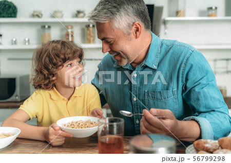 Mature father and son eating breakfast at kitchen 56799298