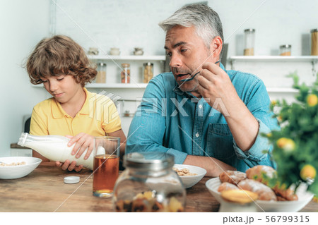 Kid making breakfast with milk, sitting near father Kid making breakfast with milk, sitting near father 56799315