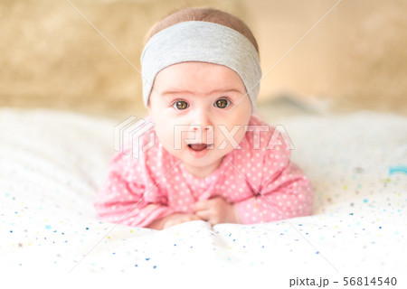 Adorable baby girl with grey headband looking towards camera and smiling. Health concept Adorable baby girl with grey headband looking towards camera and smiling. Health concept 56814540