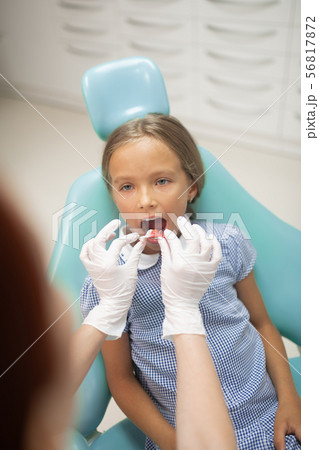 Girl opening mouth wide while dentist putting mouth guard inside Girl opening mouth wide while dentist putting mouth guard inside 56817872