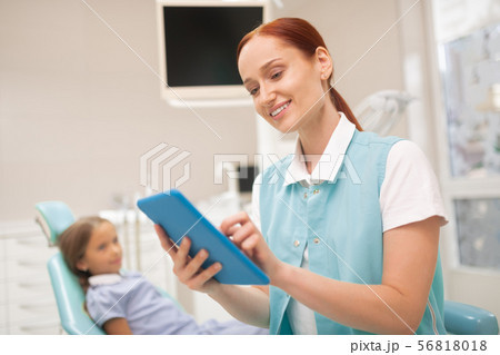 Child dentist smiling while studying clinical record Child dentist smiling while studying clinical record 56818018