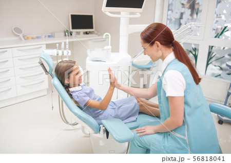 Smiling girl giving high five to her dental therapist Smiling girl giving high five to her dental therapist 56818041