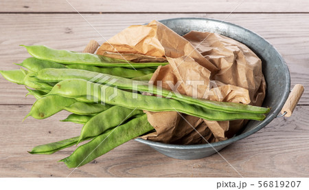 bunch of flat beans on a wooden board. 56819207