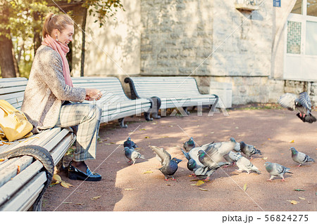 Pretty woman resting in park and feeding pigeons Pretty woman resting in park and feeding pigeons 56824275