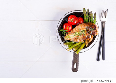 Grilled chicken breast on a cast iron skillet with grill vegetables on a wooden background, flat lay Grilled chicken breast on a cast iron skillet with grill vegetables on a wooden background, flat lay 56824931