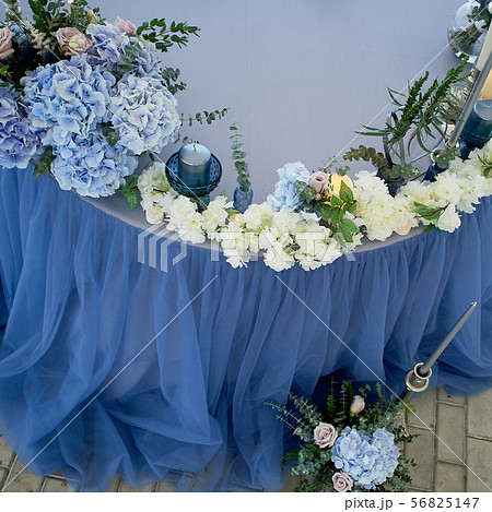 Wedding table decorated with white flowers, candles. Soft sofa with cushions, large window.Blue and Wedding table decorated with white flowers, candles. Soft sofa with cushions, large window.Blue and 56825147