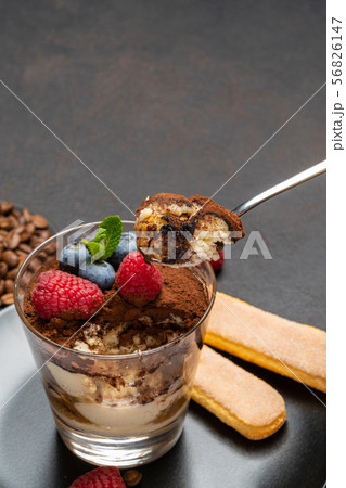Classic tiramisu dessert portion with blueberries and raspberries in a glass cup on stone serving Classic tiramisu dessert portion with blueberries and raspberries in a glass cup on stone serving 56826147