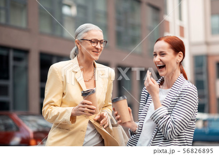 Two happy modern attractive business ladies laughing outdoors Two happy modern attractive business ladies laughing outdoors 56826895