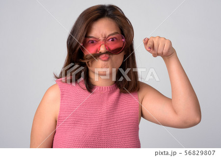 Young angry Asian woman with hair as mustache pointing at camera 56829807