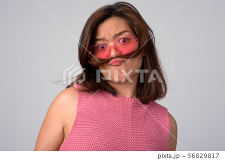 Young beautiful Asian woman wearing heart shaped glasses with hair as mustache Young beautiful Asian woman wearing heart shaped glasses with hair as mustache 56829817