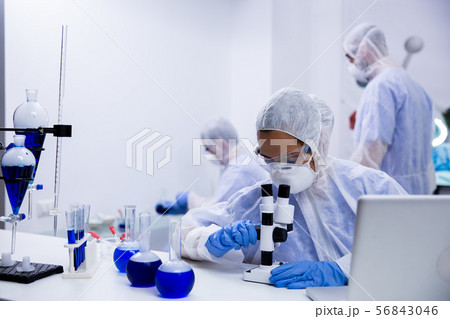 Female scientist looking at a sample of solution through 56843046