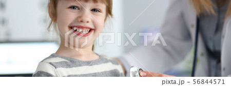 Smiling cute little girl with doctor measuring heart beat with stethoscope 56844571