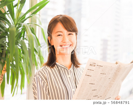 笑顔で新聞の株式欄を見るビジネスウーマン 56848791