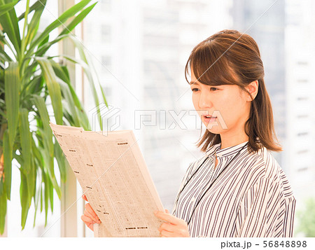 新聞の株式欄を見て悩むビジネスウーマン 56848898