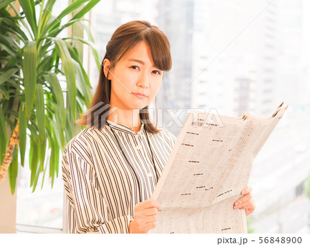 新聞の株式欄を見て悩むビジネスウーマン 56848900