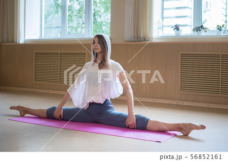 Young slim woman with blonde hair sitting on the yoga mat in split - dance studio Young slim woman with blonde hair sitting on the yoga mat in split - dance studio 56852161
