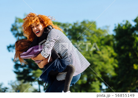 Joyful young female person embracing her daughter Joyful young female person embracing her daughter 56855149