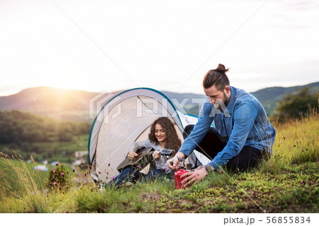 Young tourist couple travellers with tent shelter sitting in nature, resting. 56855834
