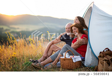 Small girl with grandparents sitting in shelter tent in nature at sunset, resting. Small girl with grandparents sitting in shelter tent in nature at sunset, resting. 56856641