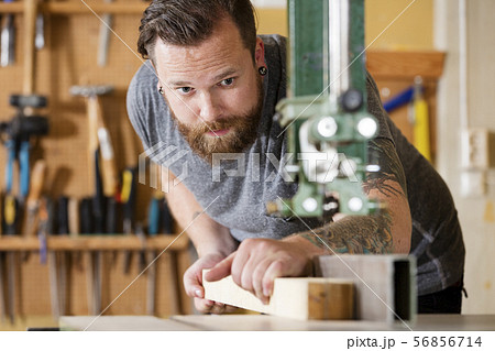 Craftsman using bandsaw for splitting wood plank in workshop 56856714